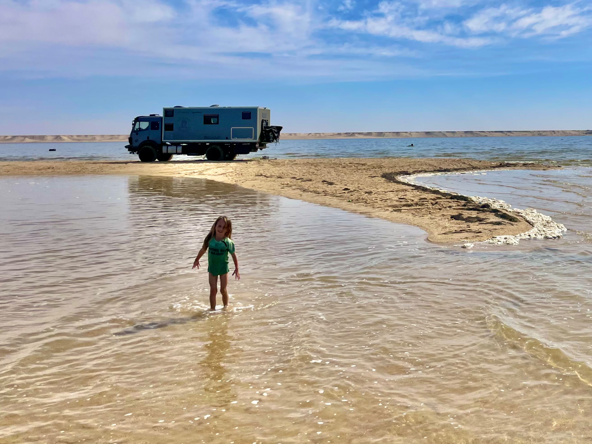 Ellie am Strand mit einem Kind im seichten Wasser